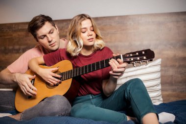 Evde dinlenip gitar çalan hoş bir çift.