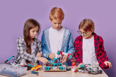 Eğitim, bilim, teknoloji konsepti. Elektrikli oyuncakları olan ve robot üreten beyaz çocuklar.