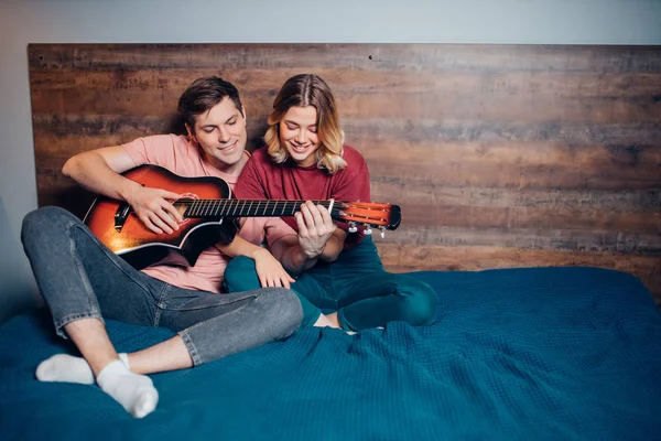 Belo jovem casal tocando guitarra no quarto juntos. — Fotografia de Stock