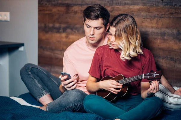 Fiatal fehér rövid hajú szőke nő játszik ukulele a férfi — Stock Fotó