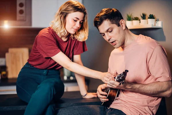 Joven rubia hembra enseñando a su amigo a jugar ukelele — Foto de Stock