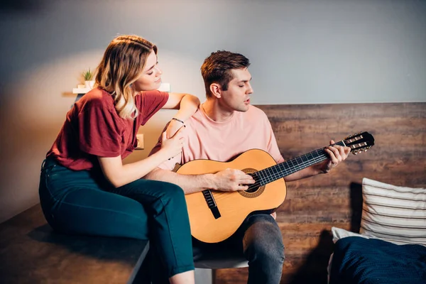 Agradable pareja pasar tiempo juntos tocando la guitarra en casa — Foto de Stock