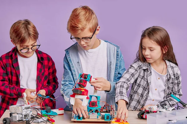 Üç konsantre çocuk robot oyuncakları monte ediyor — Stok fotoğraf