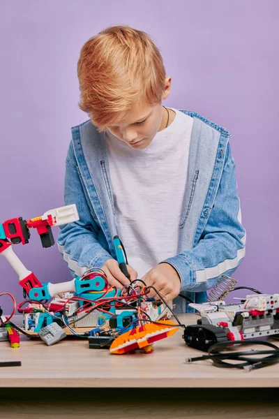 Умный мальчик в повседневной одежде собирает роботов — стоковое фото