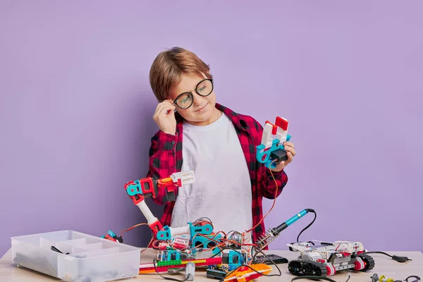 Дитина з окулярами складає роботів на столі ізольовані — стокове фото