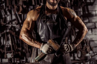 Kesilmiş kalpazan elinde çekiç tutuyor.