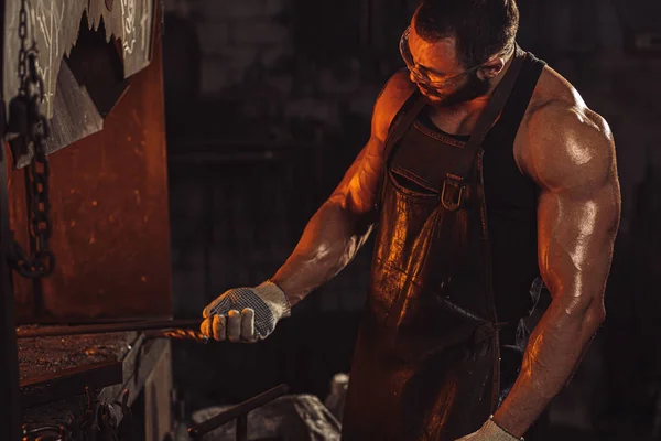 Real brutal caucasian blacksmith works in a workshop — Stock Photo, Image