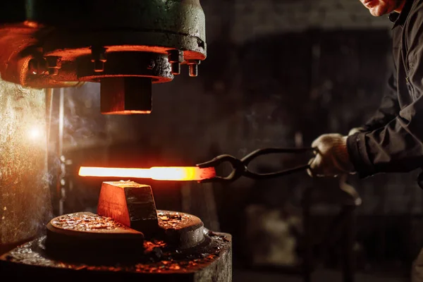 Vousatý mladý kavkazský padělatel používající hydraulický lis pro výrobu ocelových zbraní v kovárně — Stock fotografie