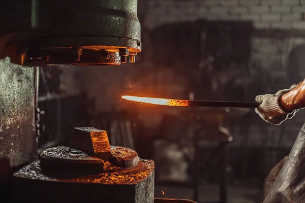 Herrero utilizando prensa hidráulica para la fabricación de armas de acero en taller de herrería — Foto de Stock