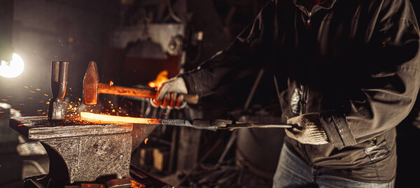 young caucasian man beating hot metal