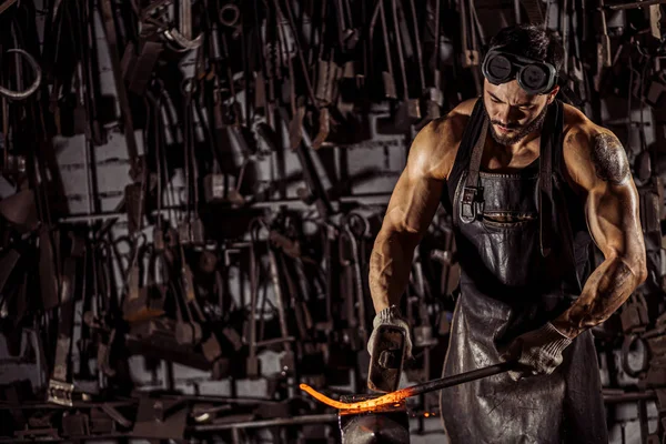 Sterke man werkt met hamer geïsoleerd in werkplaats — Stockfoto