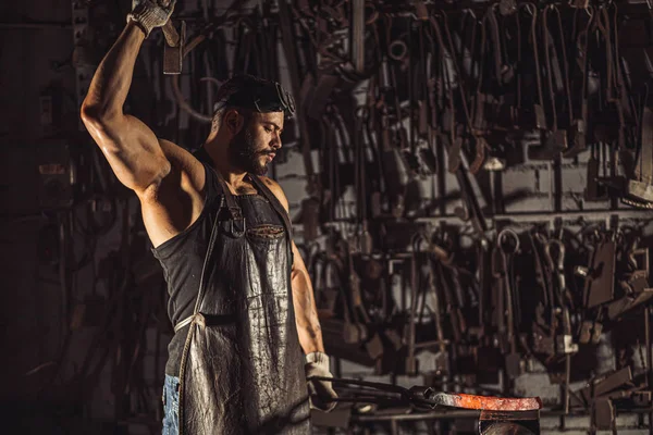 Strong man working with hammer isolated in workshop — Stock Photo, Image