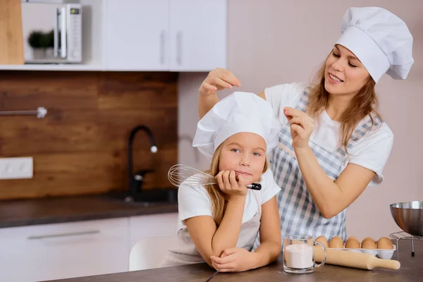 Young caucasian woman preparing daughter for baking — Stock Photo, Image