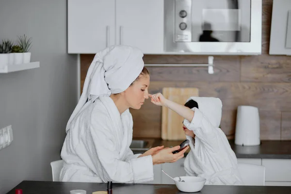 Mooie ouder en zijn dochter zitten in keuken met gezichtsmaskers — Stockfoto