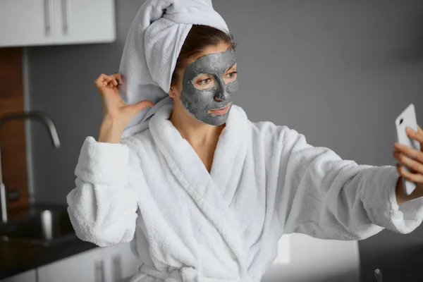Wanita cantik dengan masker wajah mengambil foto di kamar tidur — Stok Foto