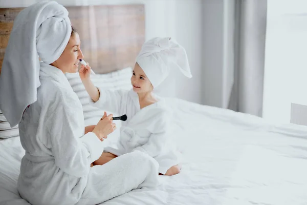 Impresionante mujer con hija sentarse sosteniendo maquillaje cepillos —  Fotos de Stock