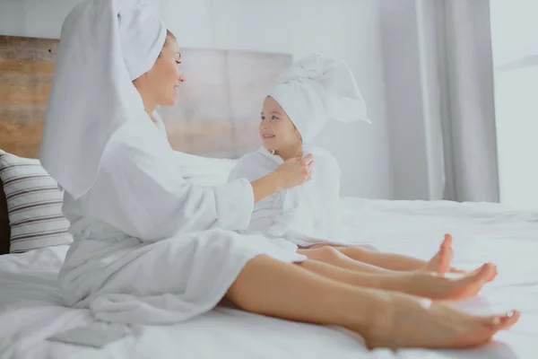 Encantadora familia, madre e hija tumbadas en la cama juntas después de la ducha —  Fotos de Stock