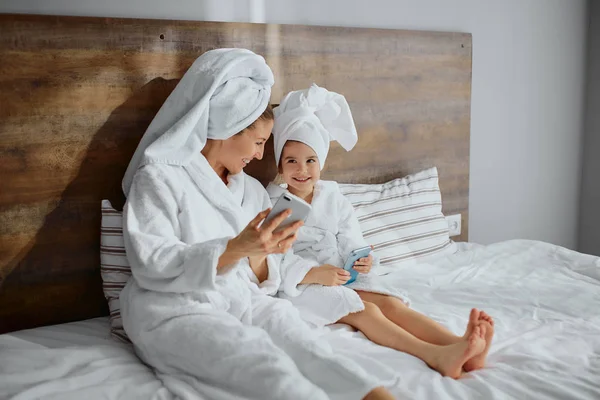 Atenta mujer cuidadosa en albornoz pasar tiempo con la hija después de la ducha —  Fotos de Stock