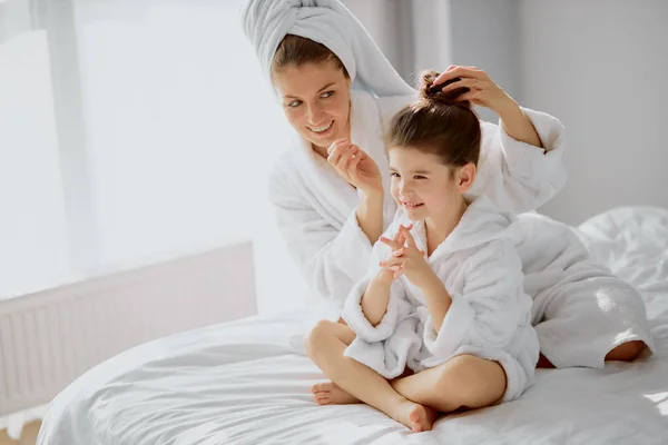 Vista lateral de la mujer y el niño que tienen tiempo libre en la cama después de la ducha — Foto de Stock