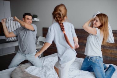 Kafkasyalı ebeveynler ve çocuklar yataktaki yastıklarla eğleniyorlar.