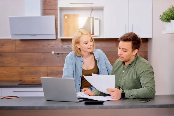 Caucasian young couple reading and analyzing bills sitting at table — Stock Photo, Image