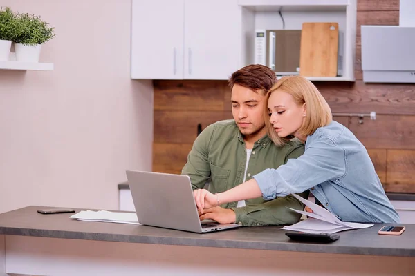 Jonge Kaukasische echtgenoten zitten met laptop en documenten thuis — Stockfoto