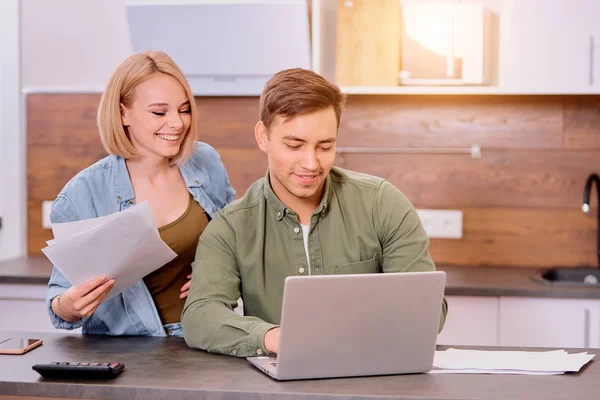 Casal feliz em casa com laptop moderno, família considerando uma hipoteca ou seguro — Fotografia de Stock