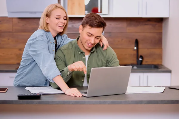 Gelukkig paar thuis gebruik laptop, jonge man bespreken contract details met lachende vrouw — Stockfoto