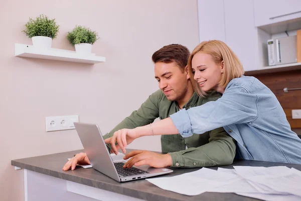 Casal feliz em casa com laptop moderno, família considerando uma hipoteca ou seguro — Fotografia de Stock