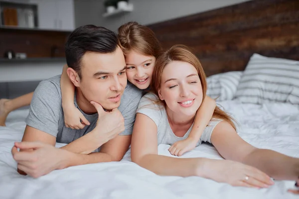 Amorosos lindos padres con su lindo niño niña en la cama —  Fotos de Stock