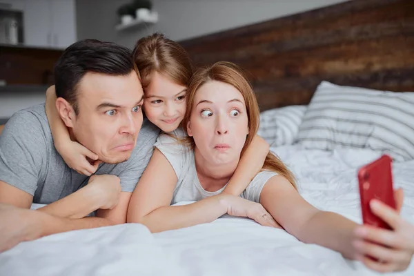 Divertida familia con niño en la cama — Foto de Stock