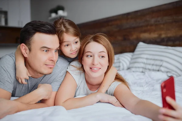 Familia feliz emocional con hija en la cama — Foto de Stock
