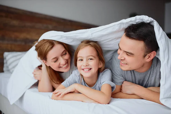 Portret vrolijke positieve familie onder deken thuis — Stockfoto