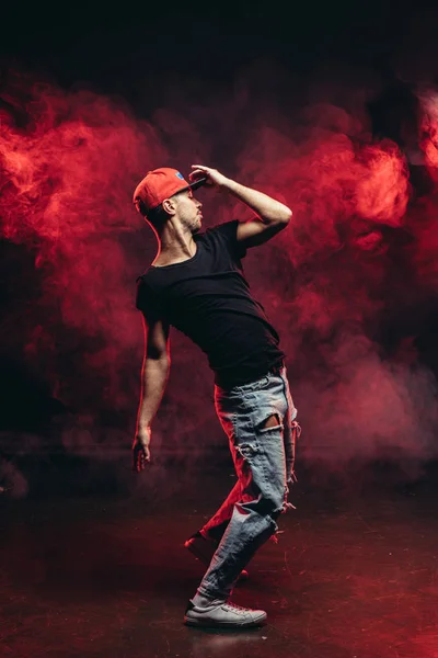 Schöner junger Mann tanzt isoliert in rot verrauchtem Raum — Stockfoto