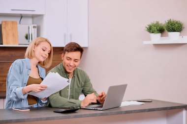 Modern dizüstü bilgisayarı olan mutlu bir çift, ev kredisi veya sigortayı düşünen bir aile.
