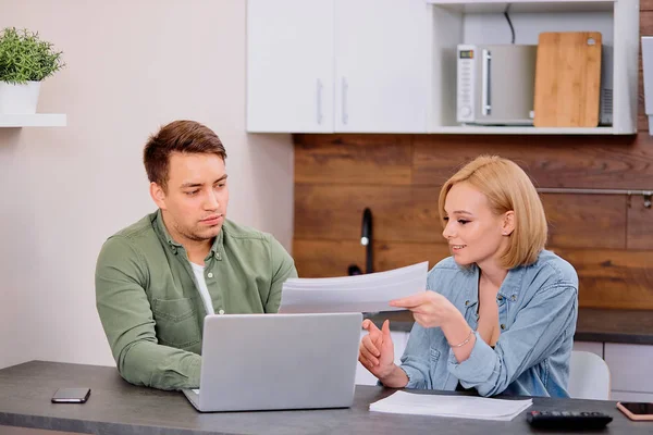 Focused young caucasian couple checking analyzing utilities bills at home
