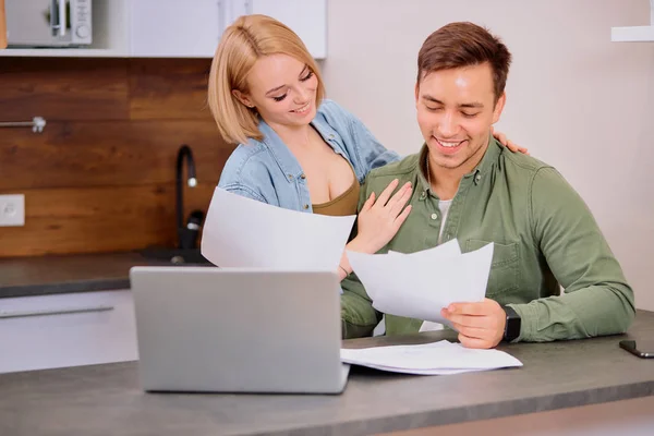 Boldog pár otthon használat laptop, fiatal férj megvitatása szerződés részleteit mosolygós feleség — Stock Fotó