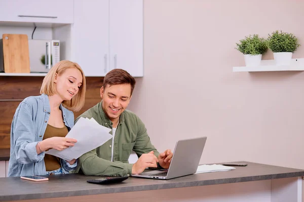 Casal feliz em casa com laptop moderno, família considerando uma hipoteca ou seguro — Fotografia de Stock