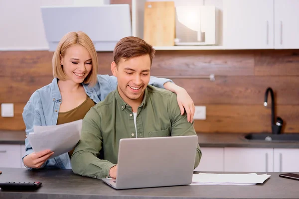 Šťastný manželský pár používat notebook doma, zatímco domácí audit — Stock fotografie