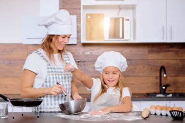 Neşeli çocuk mutfağa un serpiyor.