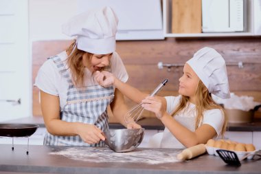 Anne ve çocuk mutfakta un tadıyorlar.