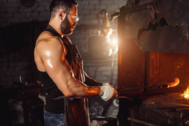 Atölyede metali ısıtan sakallı adamın yan görüntüsü