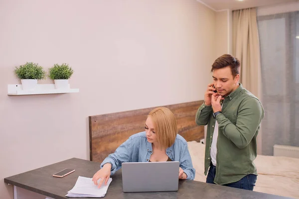 Esposa trabaja en el ordenador portátil, mientras que su marido habla por teléfono — Foto de Stock