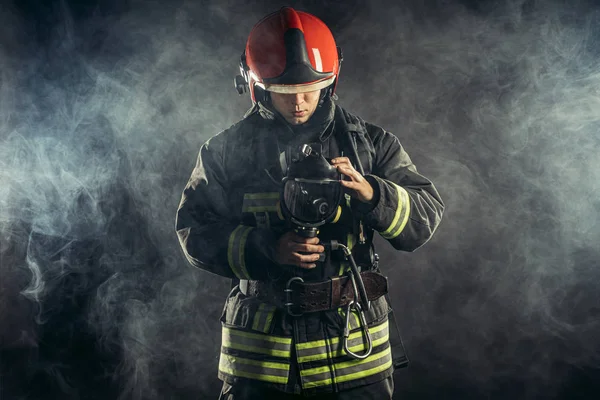 Bombeiro caucasiano em uniforme stand em fumaça — Fotografia de Stock