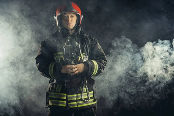 Bombeiro em uniforme em fundo fumegante — Fotografia de Stock