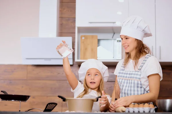 Mädchen bestreut Mehl vor dem Backen mit Mutter — Stockfoto