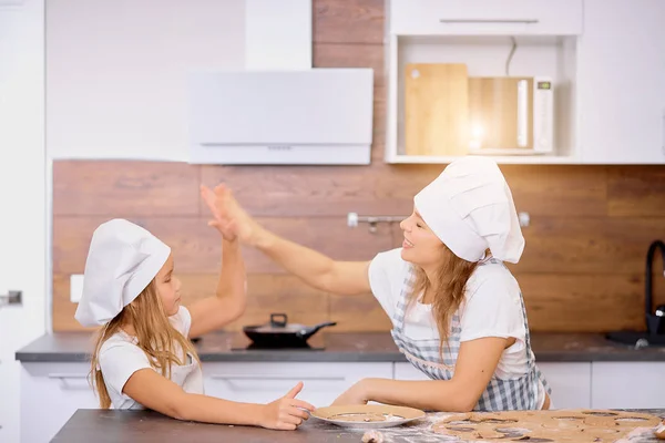 Madre e hija aplaudiendo entre sí en la cocina — Foto de Stock