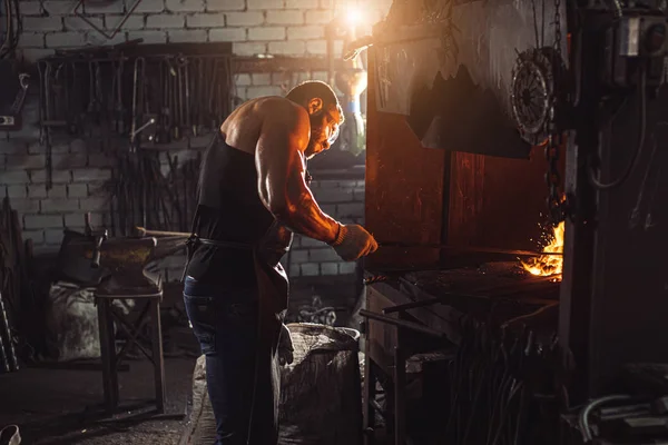 Joven herrero caucásico tradicional trabajando con fuego abierto en taller — Foto de Stock