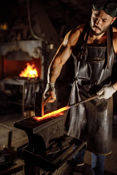 Junge Schmiede hält heißes Metall in der Hand — Stockfoto