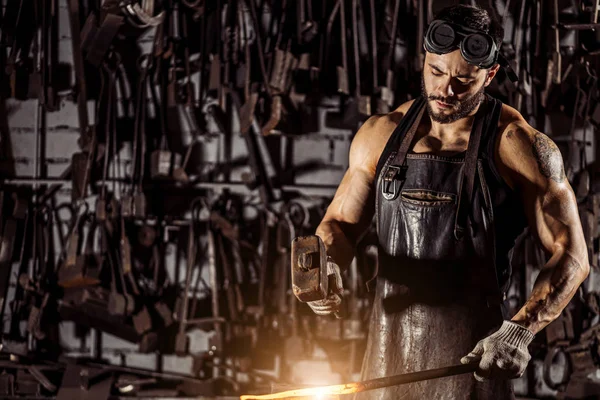 Jovem ferreiro forjando metal fundido — Fotografia de Stock